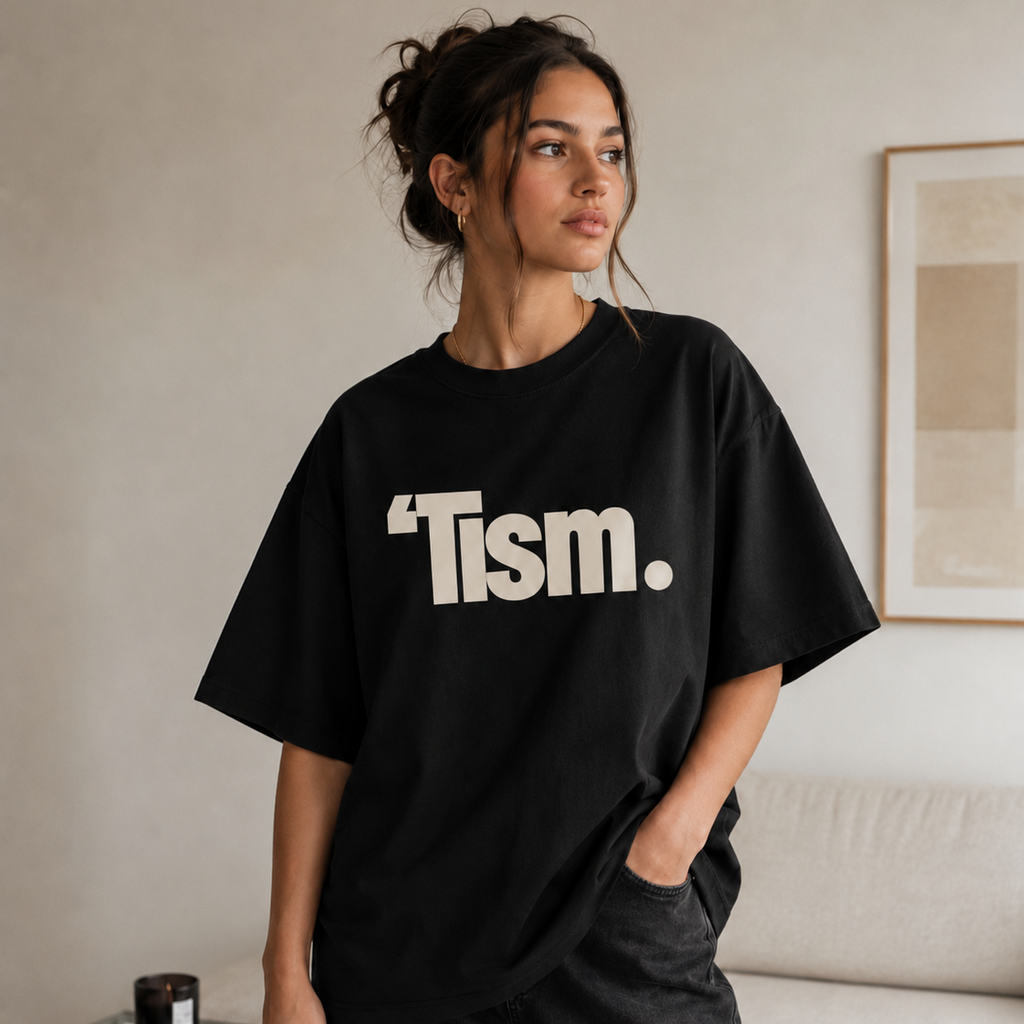 Person wearing a black t-shirt with 'Tism.' text in a living room setting